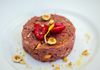 raw meat tartare macro with raspberry and nuts on white plate
