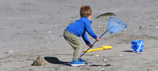 Red headed boy building sandcastles Bucket spade on a sandy beach