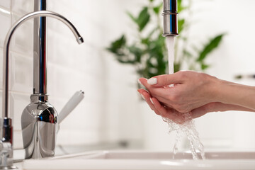 Closeup of caucasian female washing hands in sink in kitchen or bathroom after coming home for...