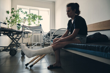 A woman with a broken leg sits on a hospital couch. Leg injury. Loss of mobility. Rehabilitation...