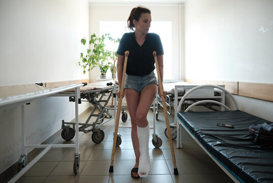 A woman with a broken leg uses orthopedic crutches. Leg injury. Loss of mobility. Rehabilitation after a fracture