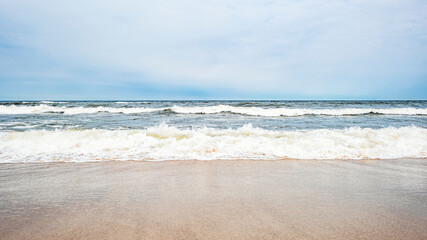 Sea waves on the beach and overcast sky