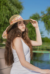 girl in a straw hat and a sundress on the background of spring and summer nature