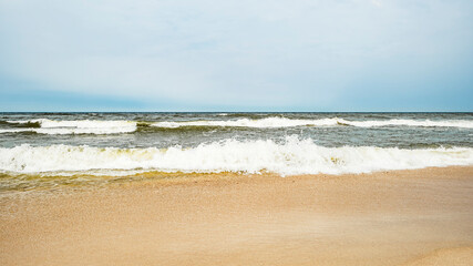 Sea waves on the beach and overcast sky