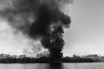 A huge column of black smoke rises from a fire near the river