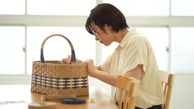 クラフトバンドでカゴを作る女性