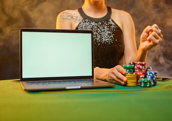 A woman in a smart dress at the table is gambling. Online casino. There is a laptop on the table, and playing cards and chips are laid out. Gambling addiction. Chance to win, hope to win big money.