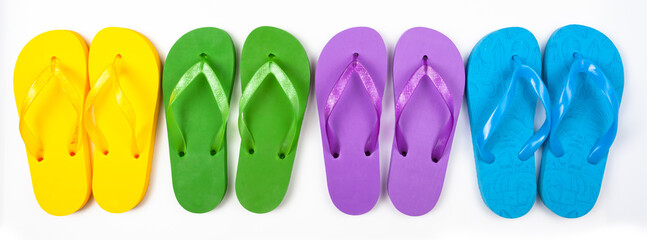 four pairs of multicolored rubber beach flip flops in a row on a white background, isolate