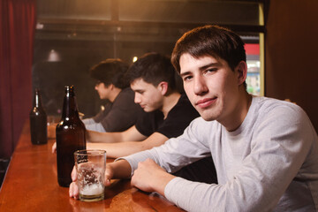 Portrait of a young man drinking beer in a bar.
