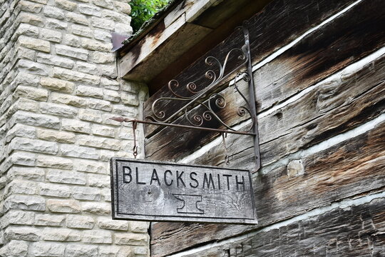 Old Wooden Blacksmith Sign On The Outside Of A Log Cabin