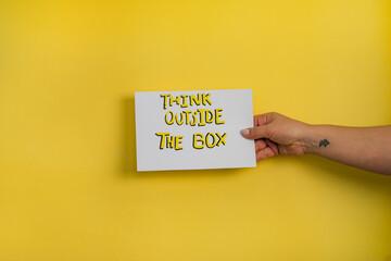 A closeup shot of a woman holding a paper with the word 