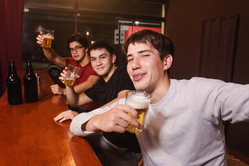 Drunk friends taking a selfie while drinking beer at the bar.
