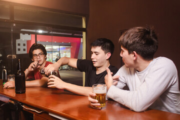 Friends chatting while drinking a beer at the bar.