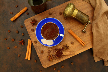 Coffee beans and ground coffee in wooden spoons on brown background. With coffee pot, blue coffee cup and coffee grinder. 