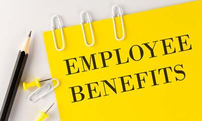 EMPLOYEE BENEFITS word on the yellow paper with office tools on white background