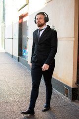 retrato de hombre caucásico con barba  formal con auriculares caminando por la ciudad 