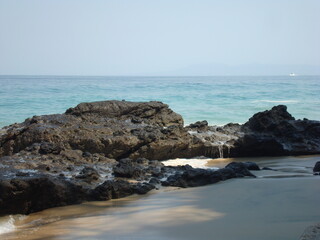 Playa rocosa a la sombra del risco, con horizonte marino 