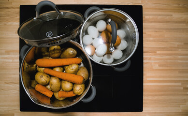 boiling hen eggs and vegetables in pans on ceramic inductive induction cooker hob