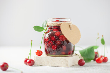 Homemade cherry jam in a jar and fresh berries on the table