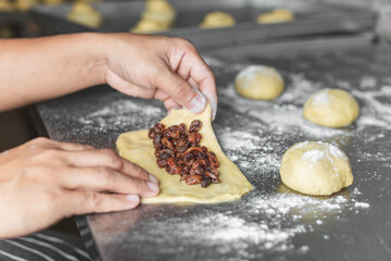 The chef is kneading the dough to make fresh bread on the kitchen table.