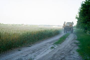 A tractor drives past an organic wheat field. Harvesting