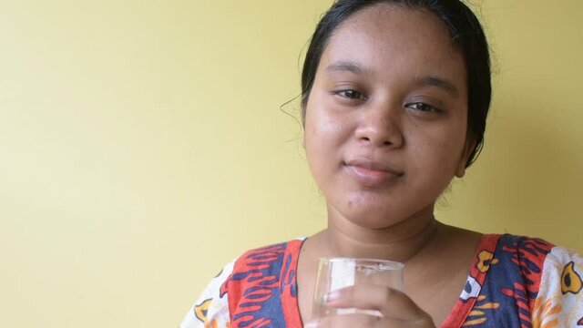 Young sick woman taking oral medicine with a glass of water at home during coronavirus pandemic situation.