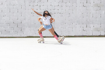 Two teenage Latin girls dressed in shorts and white t-shirt dance fun on four-roller skates