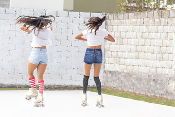 Two girls jumping and spinning on roller skates on a summer morning