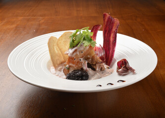 crispy pork belly with veggies and chef sauce appetiser on wood table fine dining western menu