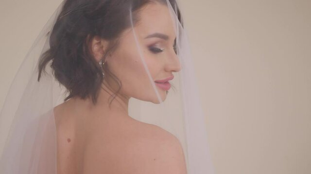 Close-up portrait of a bride in a dress with a veil that covers her head.