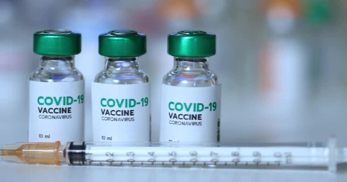 bottle or vial of covid-19 coronavirus vaccine labeled in green color and syringe. Development of coronavirus vaccine in labotory concept