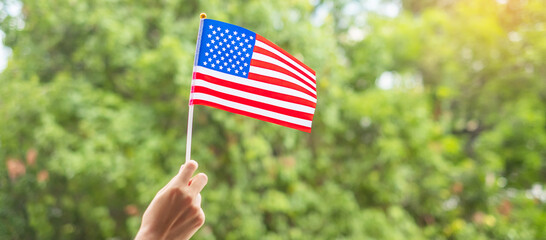 hand holding United States of America flag on green background. USA holiday of Veterans, Memorial, Independence ( Fourth of July) and Labor Day concept