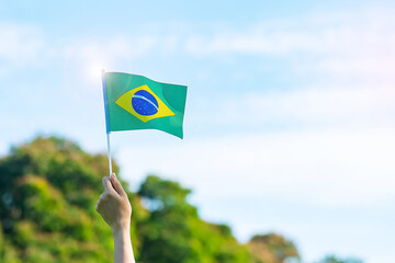 hand holding Brazil flag on blue sky background. September Independence day and Happy celebration concepts