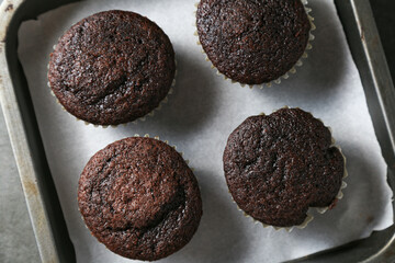 Delicious and fresh chocolate muffins on a gray ceramic table.