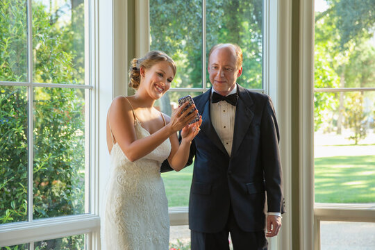 Bride showing her father picture on mobile phone screen 