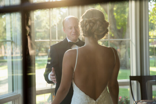 Bride and father of the bride about to embrace celebrating the wedding day, seen through window