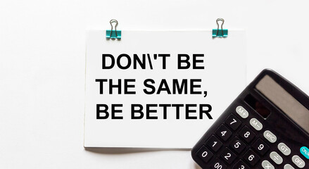 Inspirational Motivational Quote on Notepad Don't be the same, be better. White background, calculator.