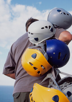 Man carrying various coloured helmets for absailing