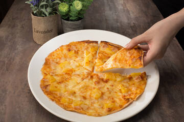 Fast food. Hawaii Chicken Pizza. Western Food. Pizza. Pineapple. Cheese. Chicken. Close up of pizza. Lady hand take a piece of pizza. Café or restaurant background. Dinner or lunch.