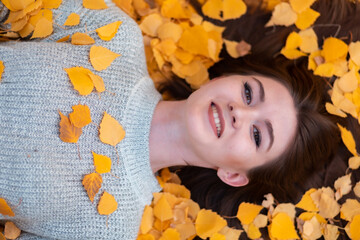 Obraz na płótnie Canvas Portrait of a woman lying over leaves and smiling