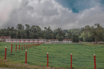 horizontal shot green landscape with wooden fences of the gardens and view of the main house Sanatorio Durán on a beautiful and cold afternoon - Cartago - Costa Rica - Central America