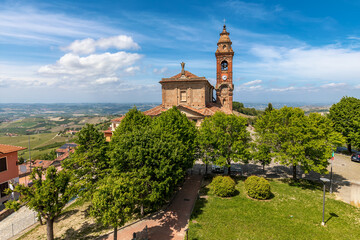 Fototapeta na wymiar Old catholic church among green trees under beautiful sky in Piedmont, Italy.