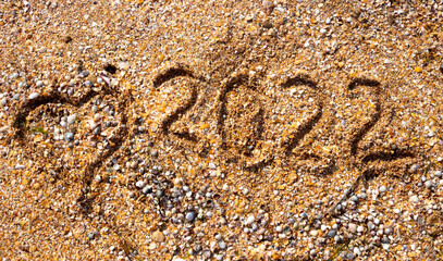The numbers 2022 and the heart on the wet sand. The concept of the New Year 2022. Summer holidays and sea trips