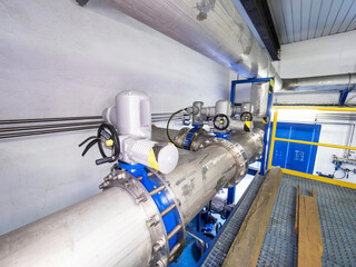 Shiny chrome steel pipes, remote controlled servo valves and blue flanges. Technical room of chemical or food inustry