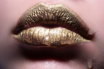 Fototapeta premium Gold lips. Woman wouth close up with golden color lipstick on lip. Glitter glossy lips biting.