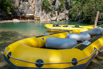 Yellow, inflatable boat for rafting down the river. Active rest in the mountains, in nature. Entertainment for a group of people. Canyon in the background. - obrazy, fototapety, plakaty