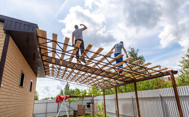 Workers install a metal shed on a wooden frame.