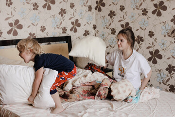 Children helping with cleaning the house, removing bed linen, doing chores. Lifestyle, brother and sister, family.