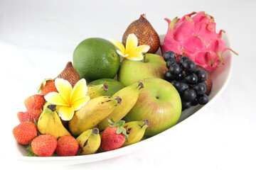 Selected tropical fruits served on a white plate, on a white background