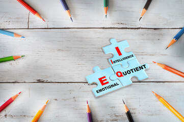 Emotional quotient and intelligence written on blue puzzle jigsaw with shadow on wooden background....